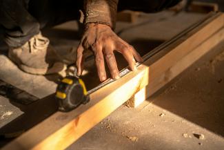 A man using a circular saw to cut a piece of wood by infinity lifespaces courtesy of Unsplash.