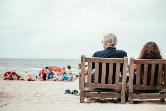 a couple of people sitting on top of a wooden bench by Peter Amende courtesy of Unsplash.