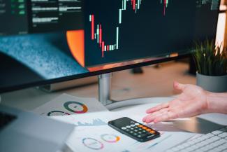 a person pointing at a calculator on a desk by Jakub Żerdzicki courtesy of Unsplash.