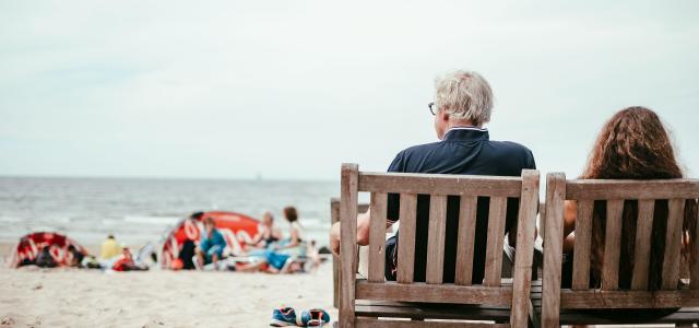 a couple of people sitting on top of a wooden bench by Peter Amende courtesy of Unsplash.